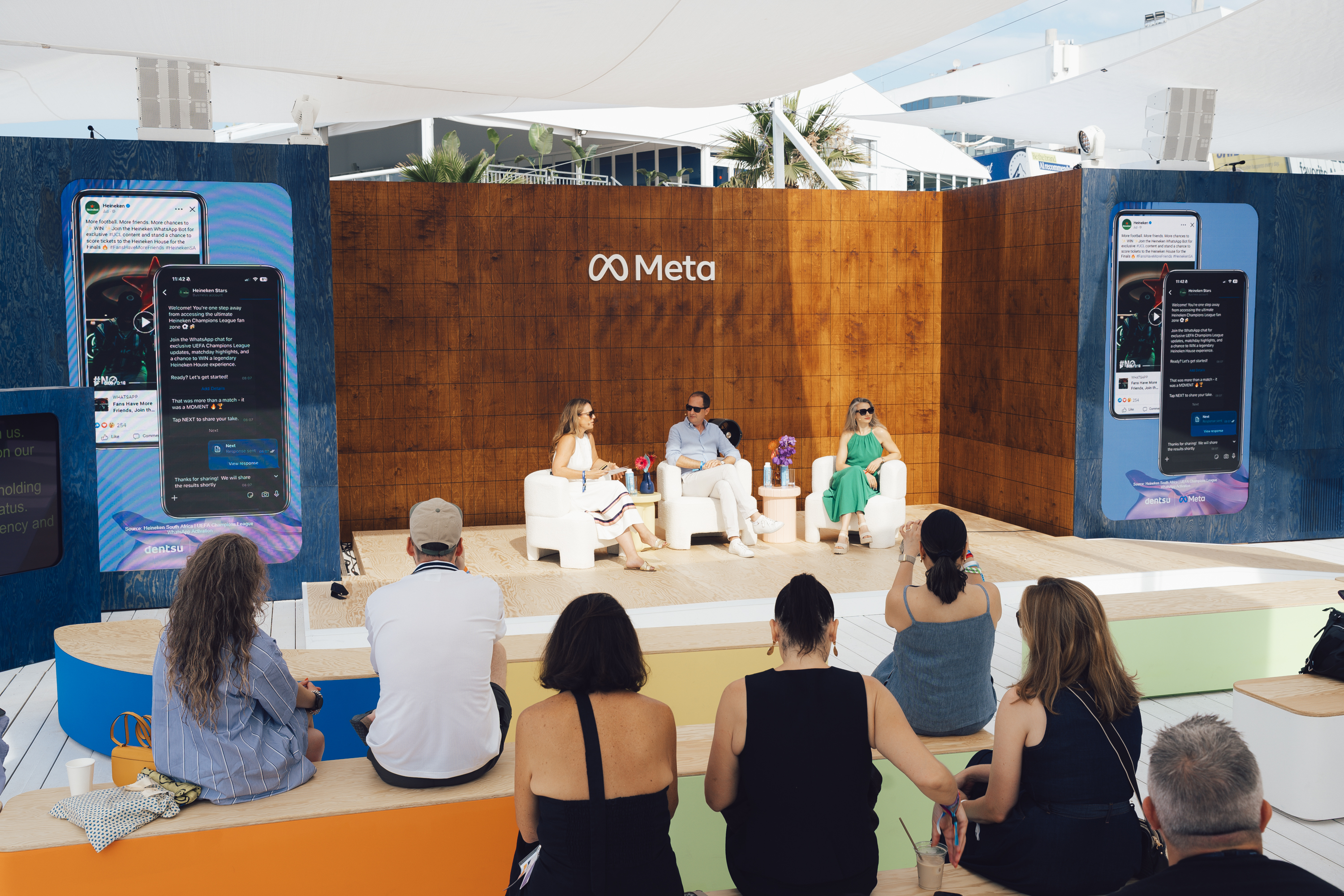 image of three people sitting on a stage with audience looking on